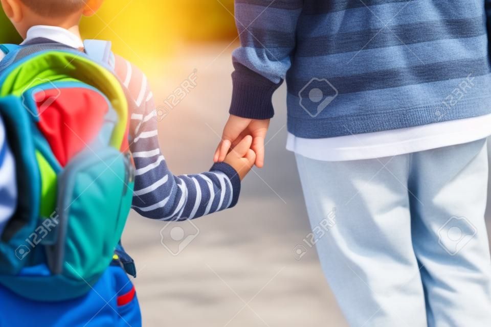 Vater Hand von kleinen Sohn hält zur Schule oder Kindertagesstätte auf dem Gehen