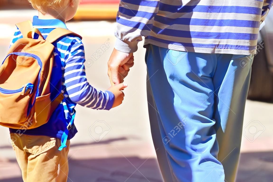Vater Hand von kleinen Sohn hält zur Schule oder Kindertagesstätte auf dem Gehen