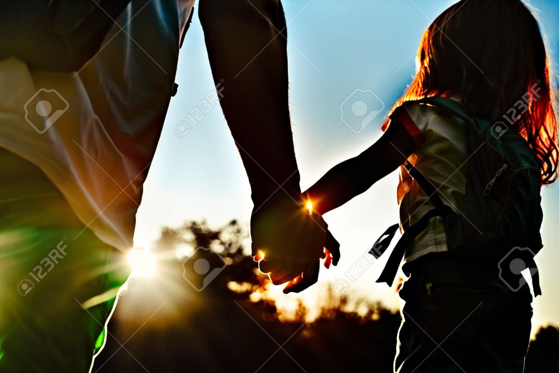 kleine jongen en meisje met rugzakken hand in hand bij zonsondergang