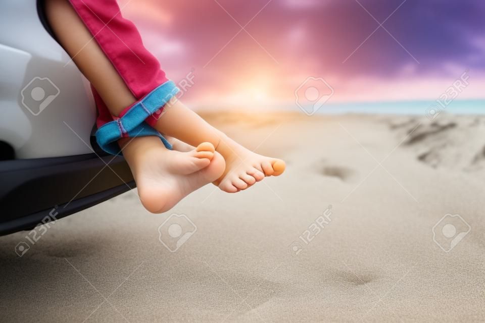 feet of little girl travel by car on beach