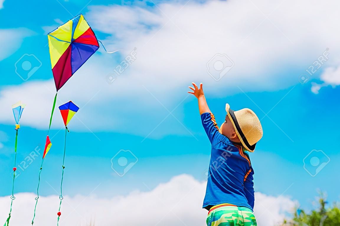 Little boy flying a kite at summer sky