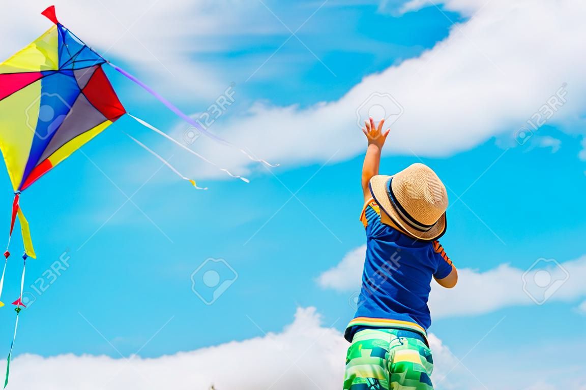 Little boy flying a kite at summer sky
