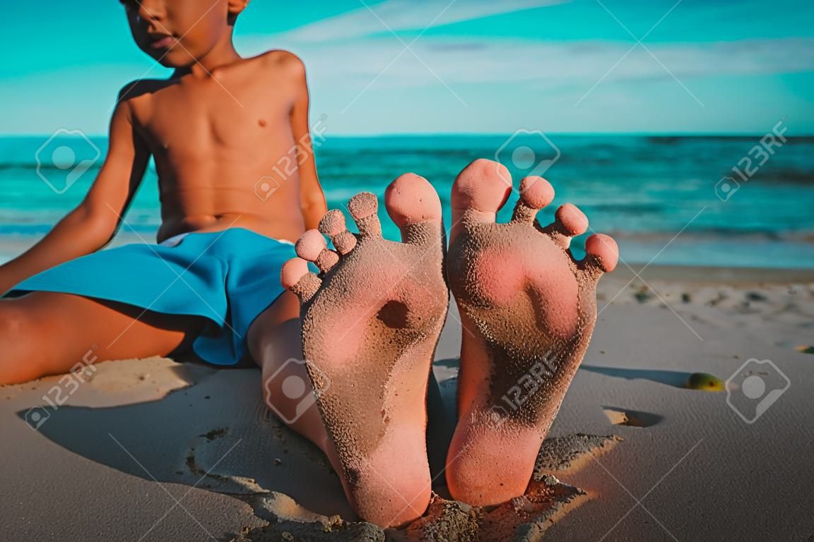 little boy relax at summer beach, focus on feet