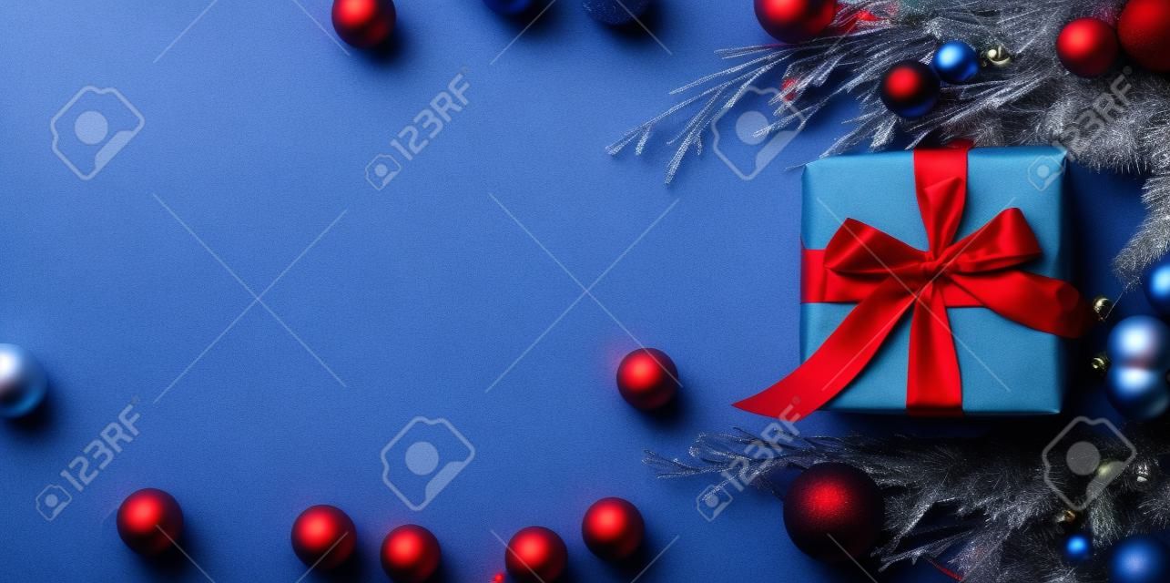 Scatole regalo di Natale avvolte in carta rossa su sfondo blu congelato. Concetto di Natale luminoso e festoso. Vista dall'alto, piatto. Copia spazio per il testo.