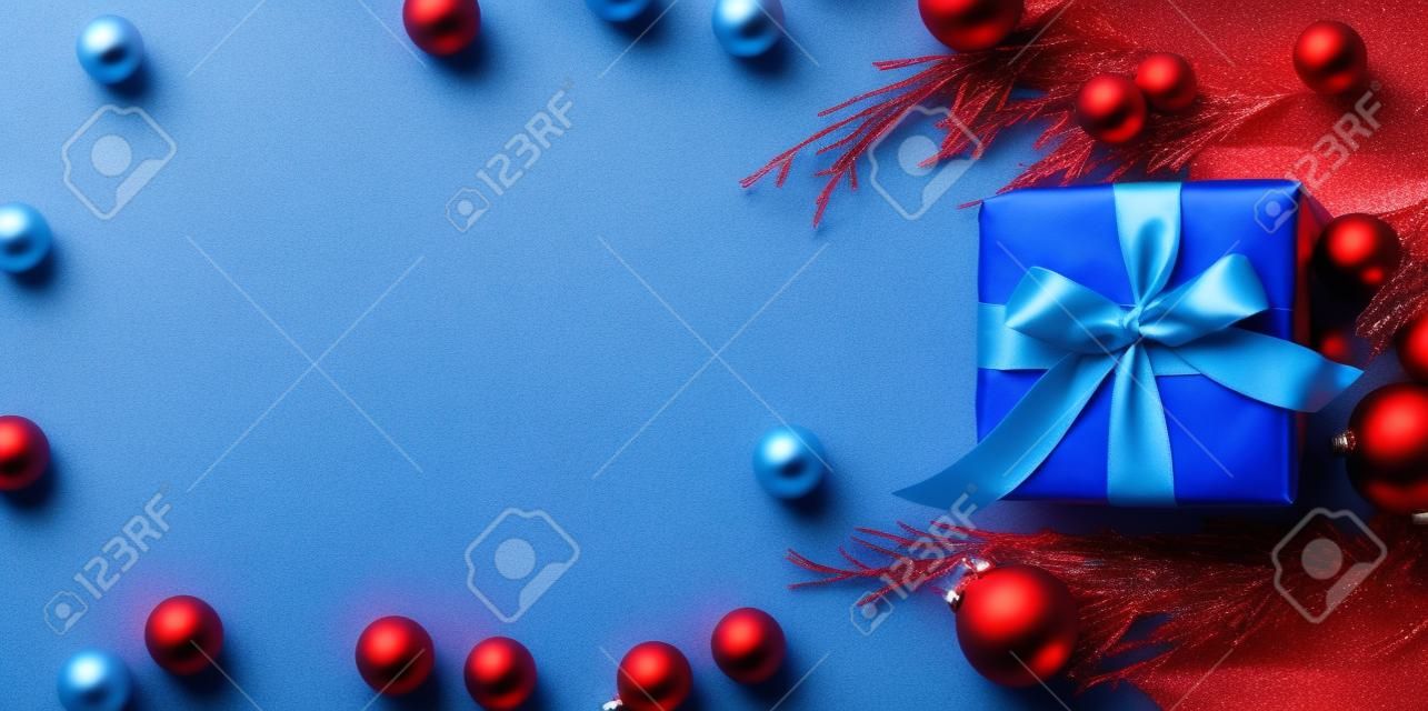Christmas gift boxes wrapped in red paper on blue frozen background. Bright and festive Christmas concept. Top view, flat lay. Copy spce for text.