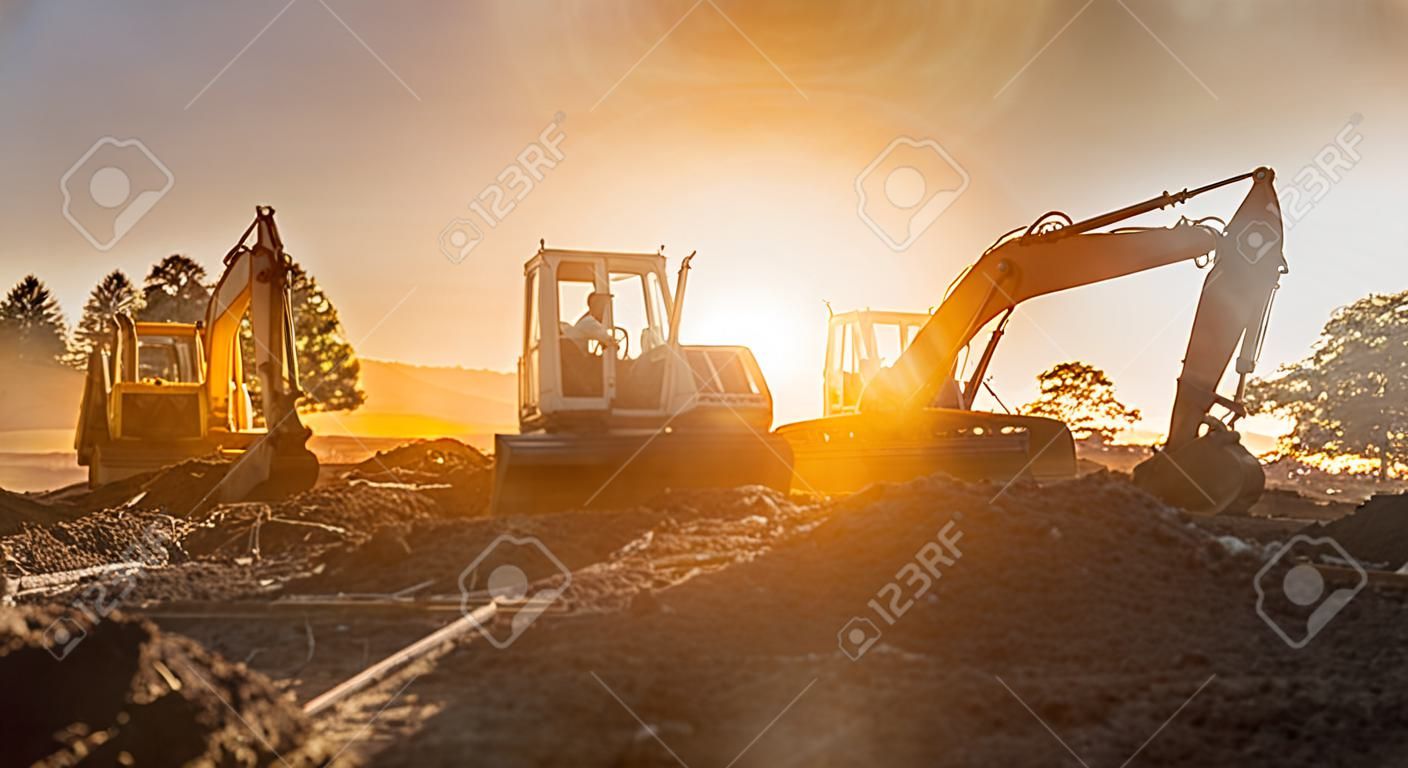 Retroexcavadora para excavar el suelo en el sitio de construcción del suelo al atardecer