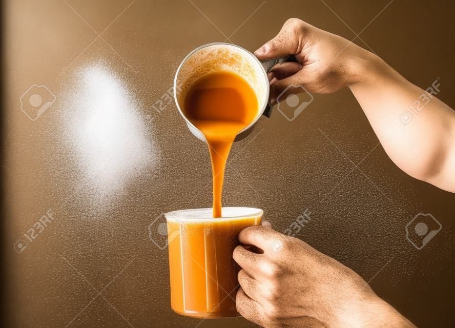 A picture of men preparing "teh tarik". Sweet milk tea been pull for mix well and create foam that is famous in Malaysia and South Asia region.