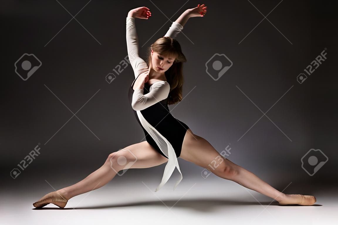 Bir nötr gri stüdyo arka plan üzerinde siyah bir mayo ve beyaz gömlek giyen güzel ince genç kadın, modern caz, çağdaş tarzı ballet dancer