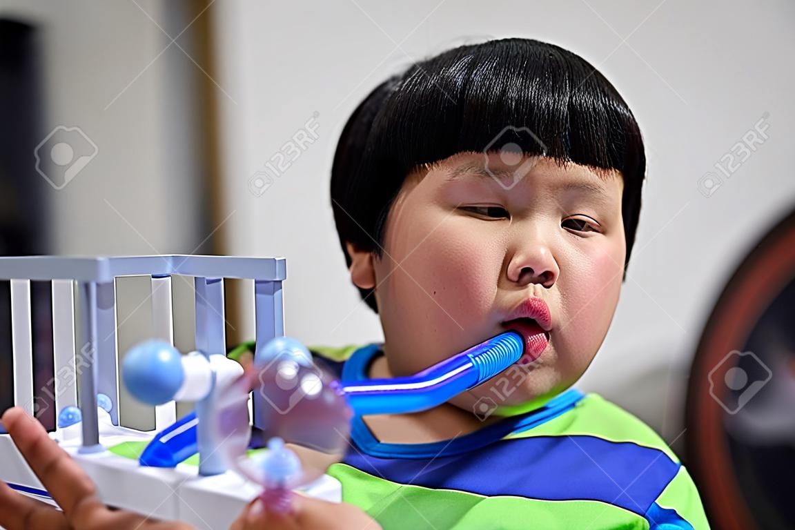 Un gros garçon teste et administre des poumons avec un séchoir à trois billes.