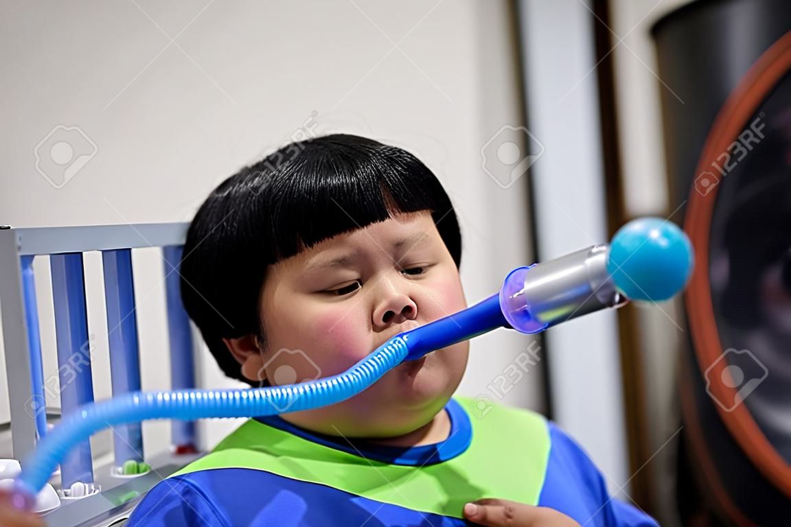 Un gros garçon teste et administre des poumons avec un séchoir à trois billes.