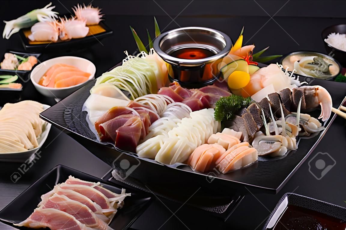 돼지고기, 쇠고기, 새우, 오징어, 해산물 및 신선한 야채로 구성된 인기 요리인 샤브샤브 또는 스키야키. 일본 식당에서 끓는 냄비와 함께 테이블에 놓습니다.