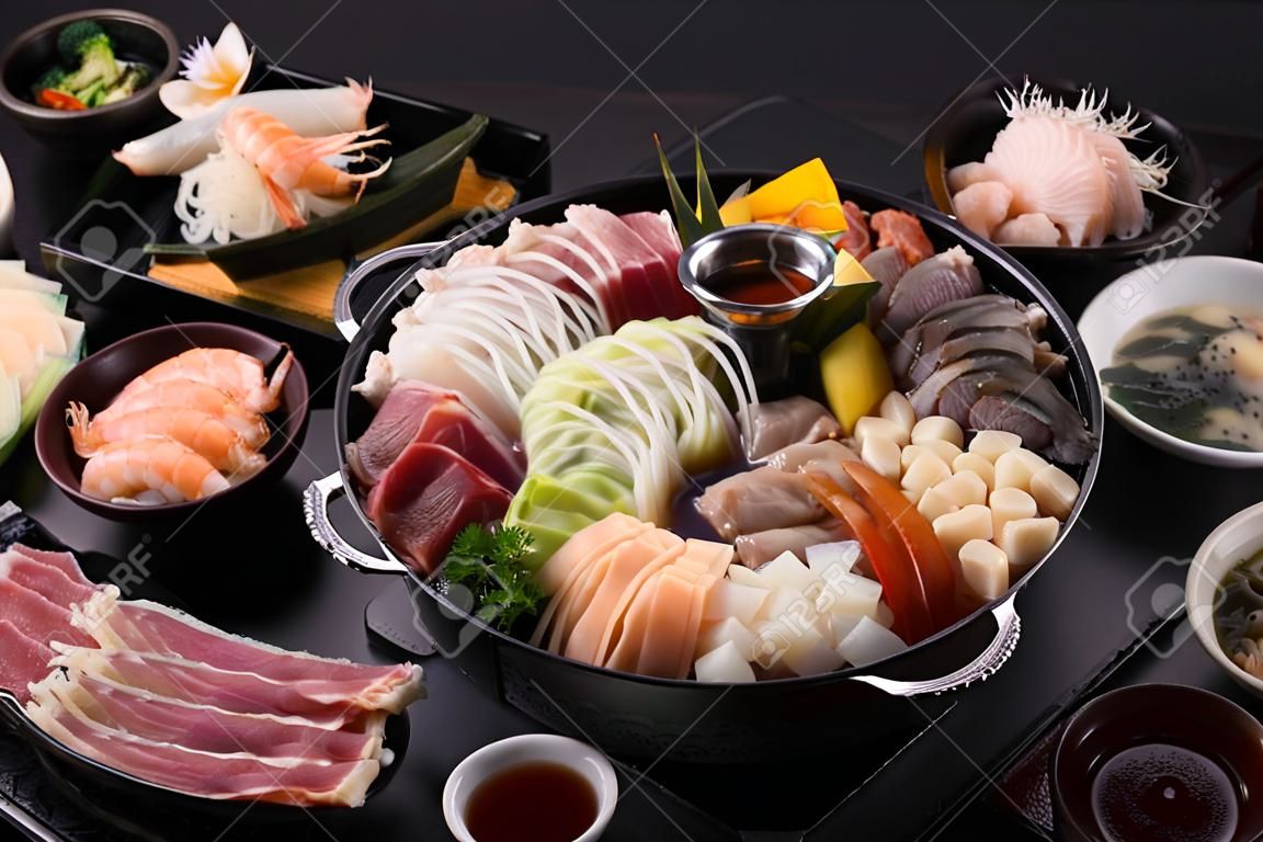 しゃぶしゃぶまたはすき焼きは、豚肉、牛肉、エビ、イカ、シーフード、新鮮な野菜の人気料理です。日本食レストランで沸騰した鍋を置いてテーブルに置きます。