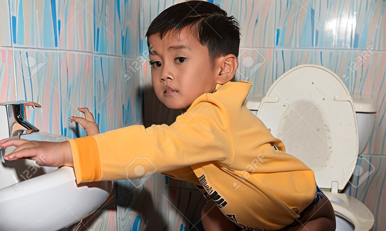 cute child little asian boy defecate in toilet