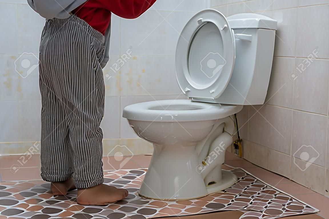Маленький азиатский мальчик мочится в туалете
