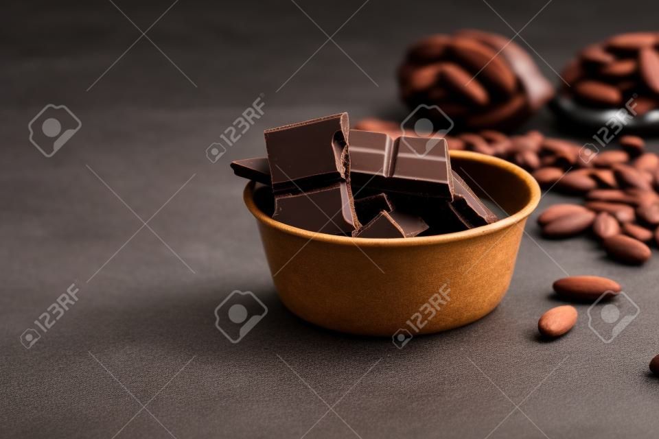 Dark chocolate pieces  and cocoa beans on table