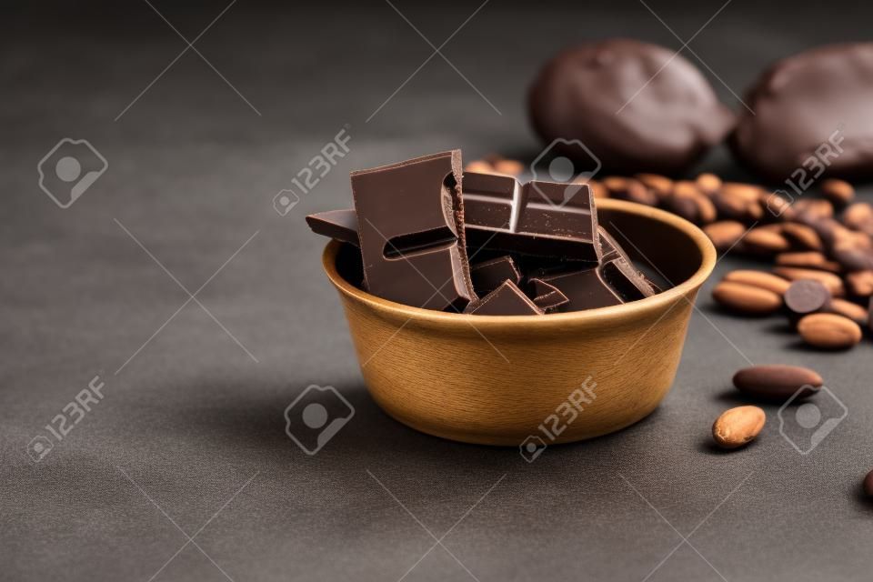 Dark chocolate pieces  and cocoa beans on table