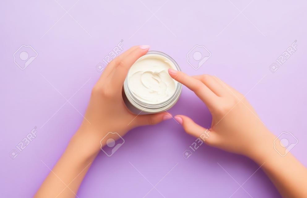 Crème hydratante pour le corps dans un pot sur fond lilas