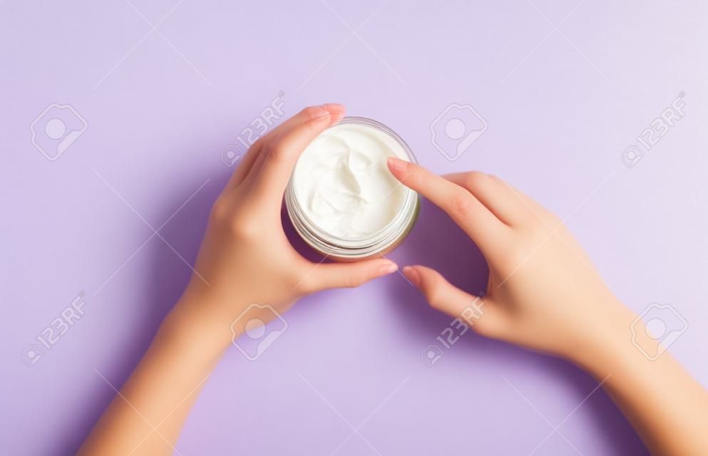 Crème hydratante pour le corps dans un pot sur fond lilas