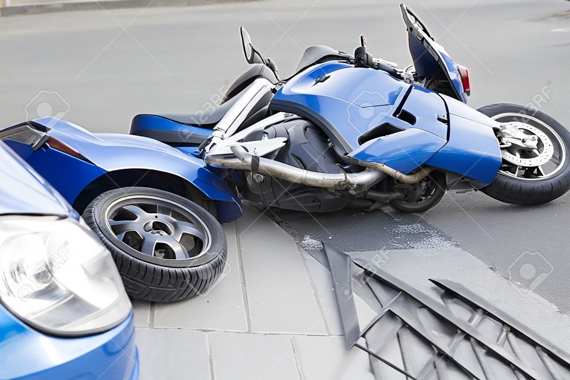 La moto azul accidente con un coche azul. La motocicleta se estrelló en el parachoques del coche en la carretera. La motocicleta se encuentra en la carretera cerca del coche.