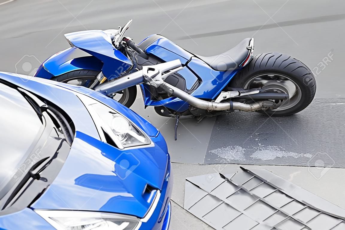 La moto azul accidente con un coche azul. La motocicleta se estrelló en el parachoques del coche en la carretera. La motocicleta se encuentra en la carretera cerca del coche.