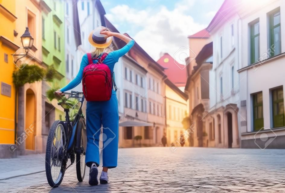 Voyage Slovénie, Europe. Jeune fille avec sac à dos et vélo urbain dans la vieille rue du centre historique de Ljubljana. Une femme voyageuse explore les sites touristiques de la ville européenne. La vie locale à Ljubljana.