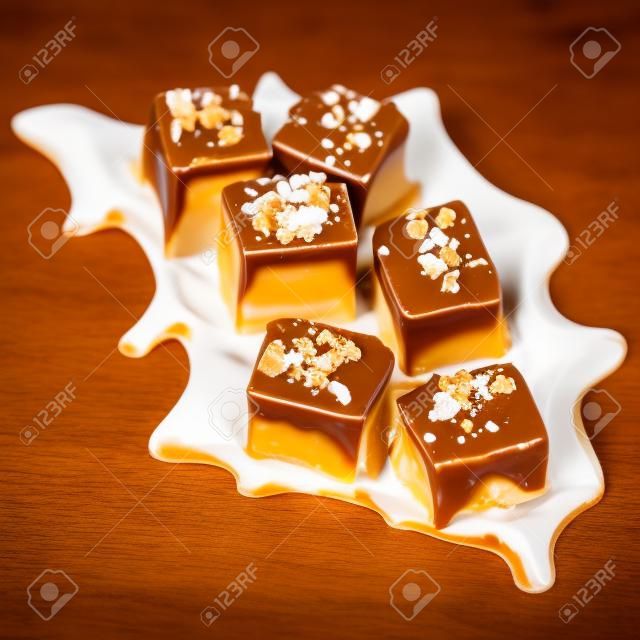 Caramelos salados del dulce de azúcar del caramelo aislados en el fondo blanco. Salsa de caramelo de caramelo dorado. Trozos de caramelo con sal marina, macro