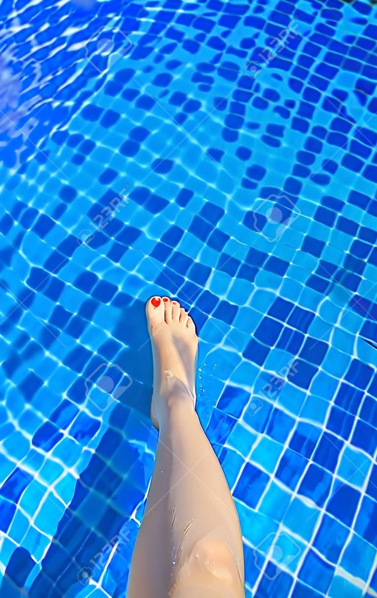 Piedi della donna in piscina in una calda giornata estiva