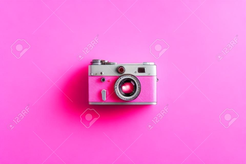 Retro film camera on a pink background. View from above.