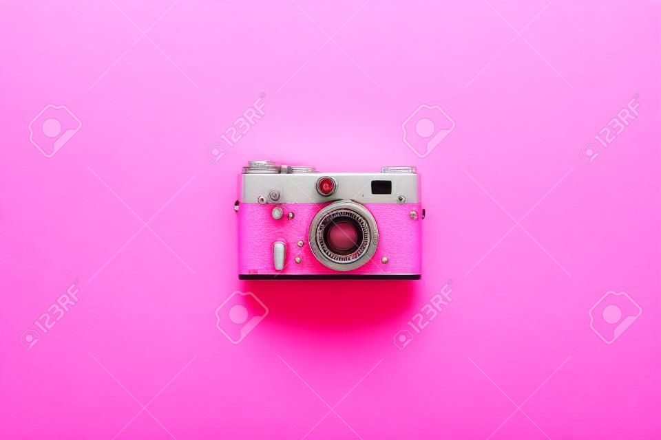 Retro film camera on a pink background. View from above.