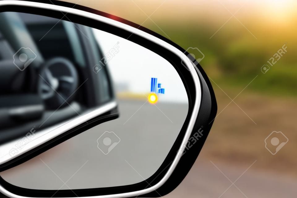 Icona della spia di avvertimento del sistema di monitoraggio dei punti ciechi nello specchietto retrovisore laterale di un veicolo moderno.