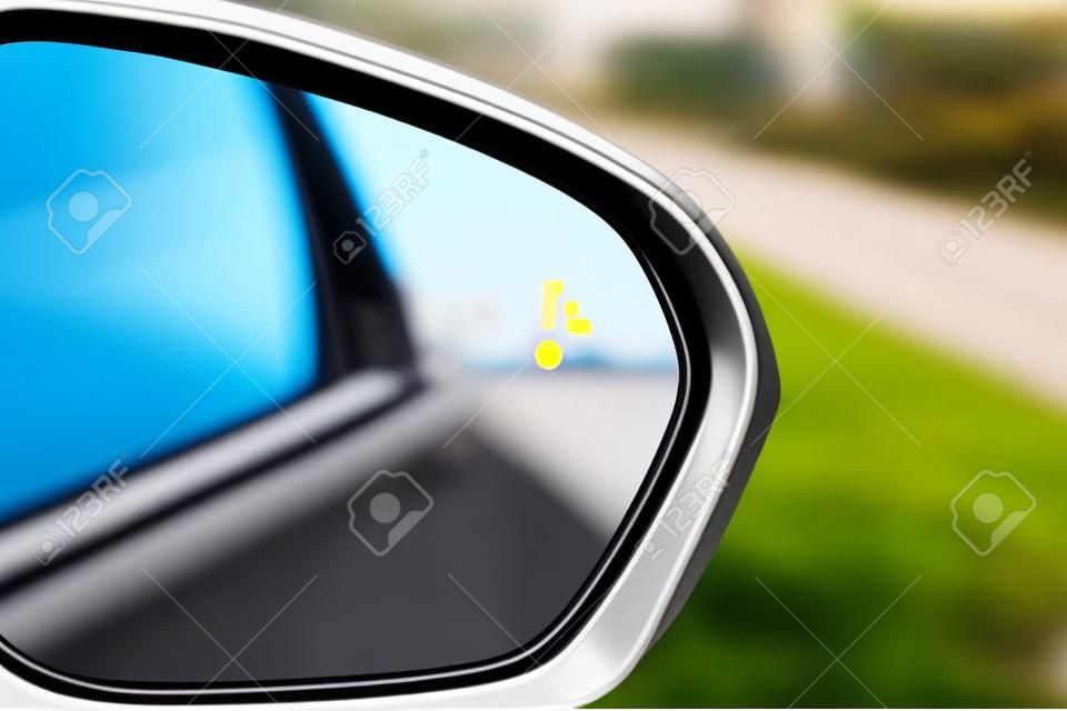 Icona della spia di avvertimento del sistema di monitoraggio dei punti ciechi nello specchietto retrovisore laterale di un veicolo moderno.