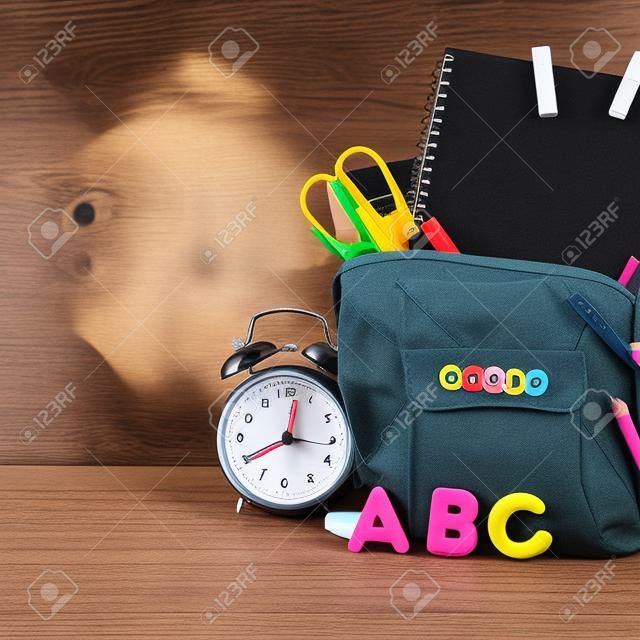 Back to school Accessories for school on a dark background Pencils Plasticine letters Letters Alarm clock Briefcase Chalk Copy spac