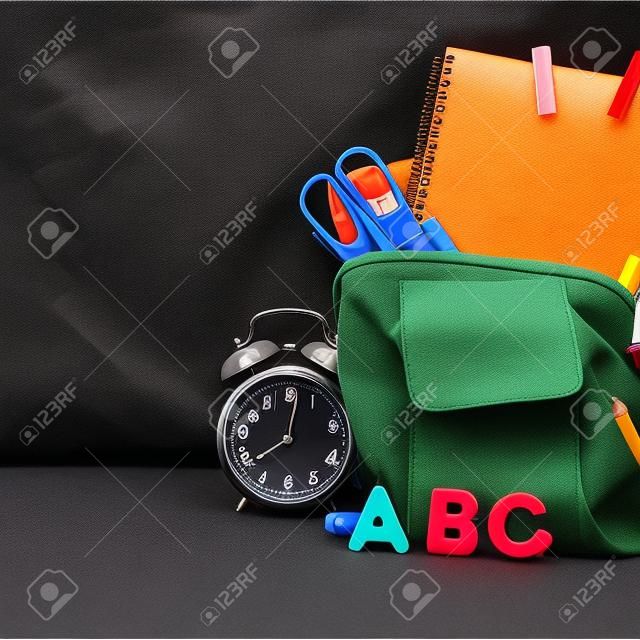 Back to school Accessories for school on a dark background Pencils Plasticine letters Letters Alarm clock Briefcase Chalk Copy spac