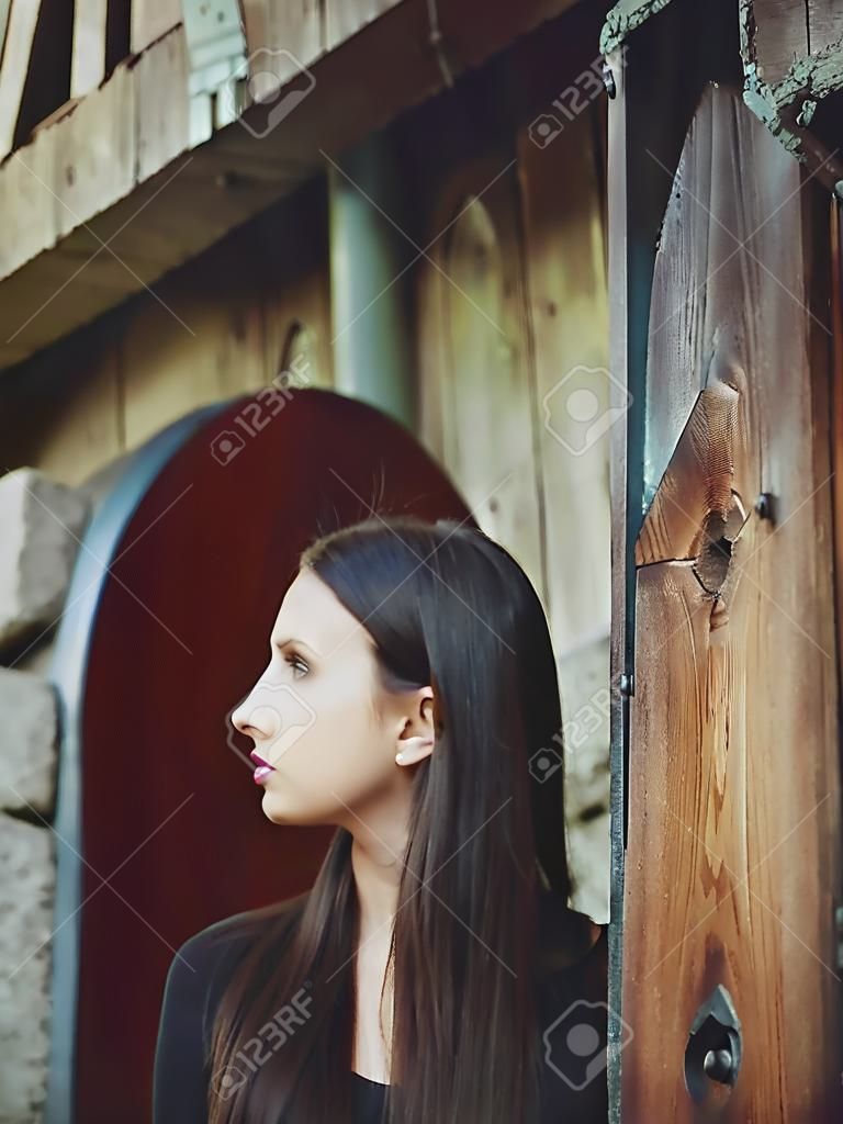 Portrait of a pretty dark-haired girl on the background of an old building.