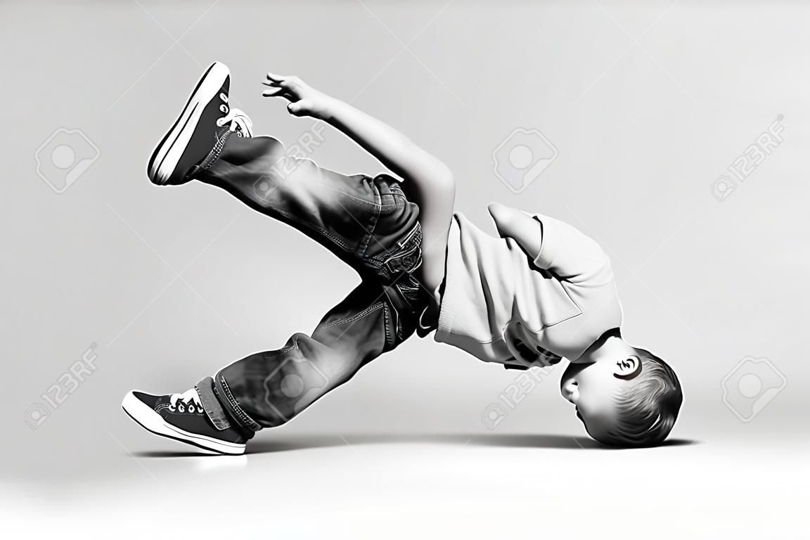 ブレイク ダンスの子供。少しブレーク ダンサー ダンス スタジオで彼の技術を示します。ヒップホップ ダンサーの少年がスタジオの背景上で実行します。黒と白の写真