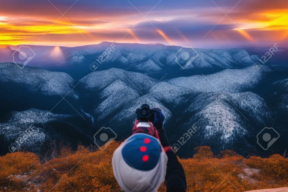 Geniet van reizen met piek van de berg. Een backpacker hand met een digitale camera op het hoogtepunt van de berg om een foto van panorama berg uitzicht met zonsondergang lichtstralen te maken