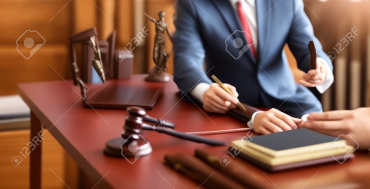 Klient klienta podpisuje umowę i omawia interesy z konsultantami prawnymi, notariuszem lub prawnikiem z laptopem i drewnianym młotkiem sędziego na biurku w biurze sali sądowej, koncepcja obsługi prawnej