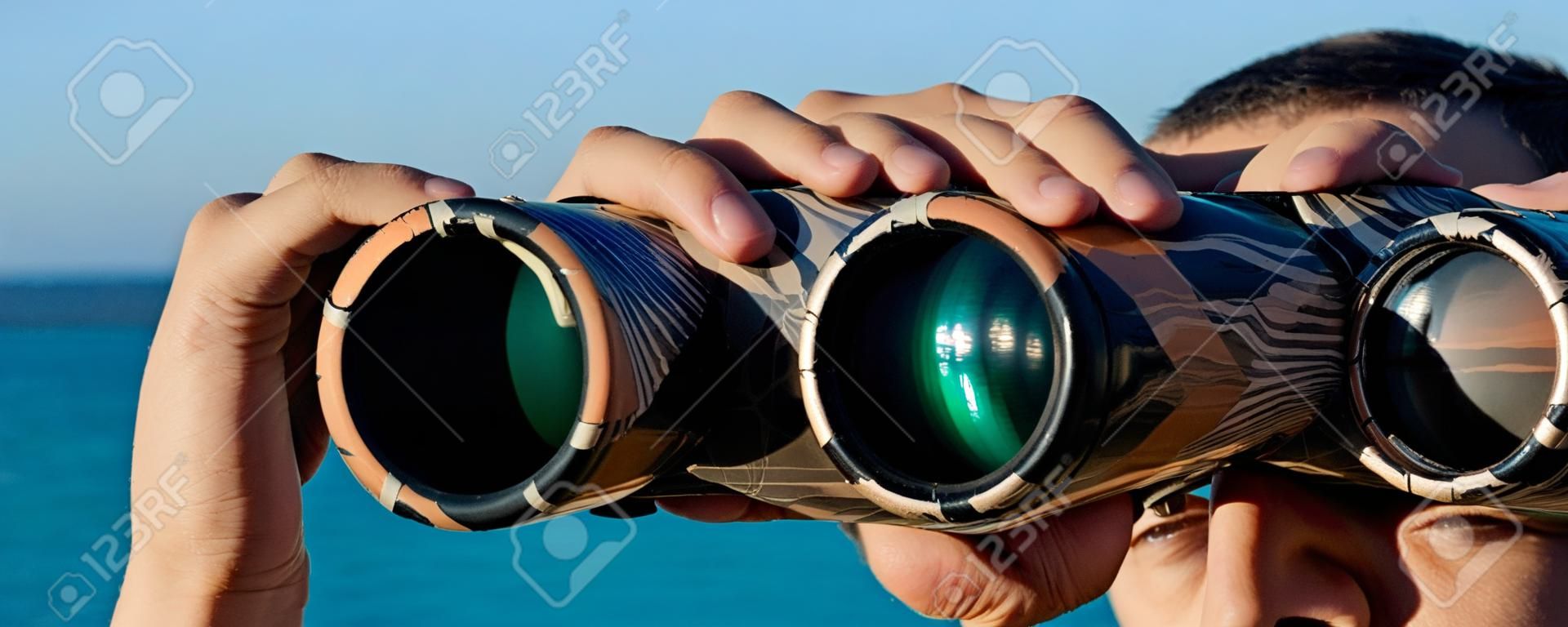 un hombre está buscando a los binoculares en el mar