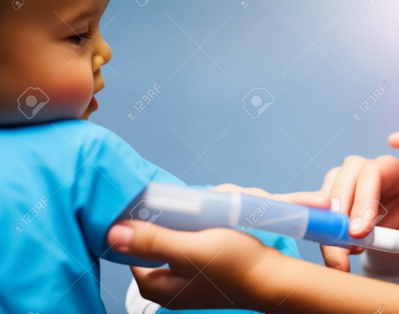 Medico, che danno al bambino una enorme iniezione nel braccio, shallow DOF