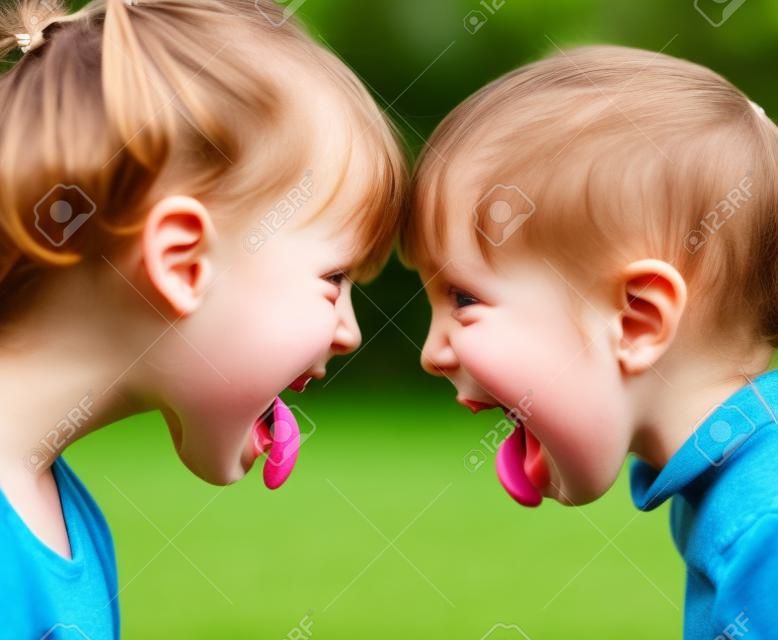 Zwei kleine Mädchen, unfreundlich Stick Zungen gegenseitig necken