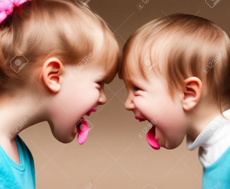 Two little girls unfriendly stick out tongues teasing each other