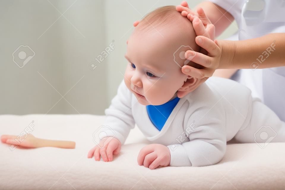 Zes maanden baby meisje die osteopathische of chiropraktische behandeling in pediatrische kliniek. Handmatige therapeut manipuleert chils hoofd en nek