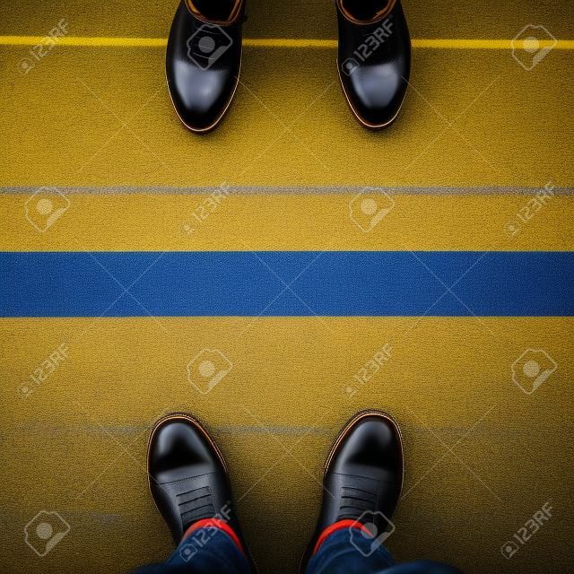 Twee paar schoenen staan op loopbrug met gele lijn gescheiden