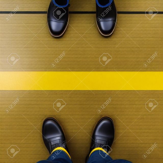 Twee paar schoenen staan op loopbrug met gele lijn gescheiden