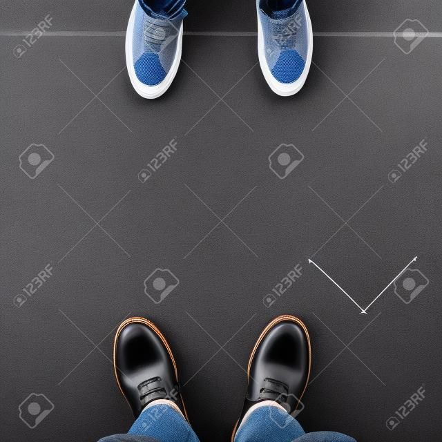 Two pairs of shoes standing on walkway with arrows