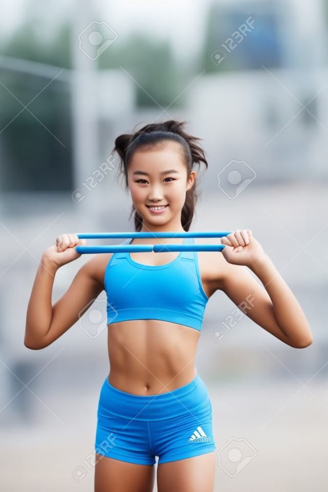 Een jong, mooi meisje van slank lichaam, gekleed in een sportuniform, brengt tijd door op een sportveld en voert fysieke oefeningen uit. Lifestyle