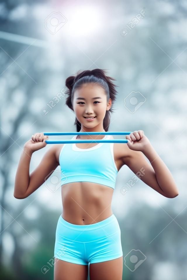 Uma jovem e bonita garota de corpo esbelto, vestida com um uniforme esportivo, passa o tempo em um campo esportivo e realiza exercícios físicos.