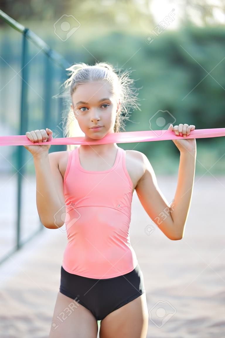 スポーツユニフォームに身を包んだ細身の若くてかわいい女の子がスポーツグラウンドで時間を過ごし、身体運動を行います。ライフスタイル