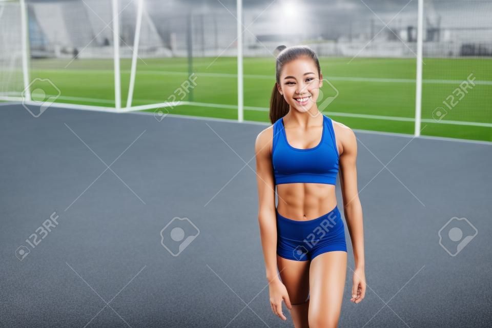 Chica guapa joven de un culturismo delgado, vestida con un uniforme deportivo, pasa tiempo en un campo de deportes. Estilo de vida