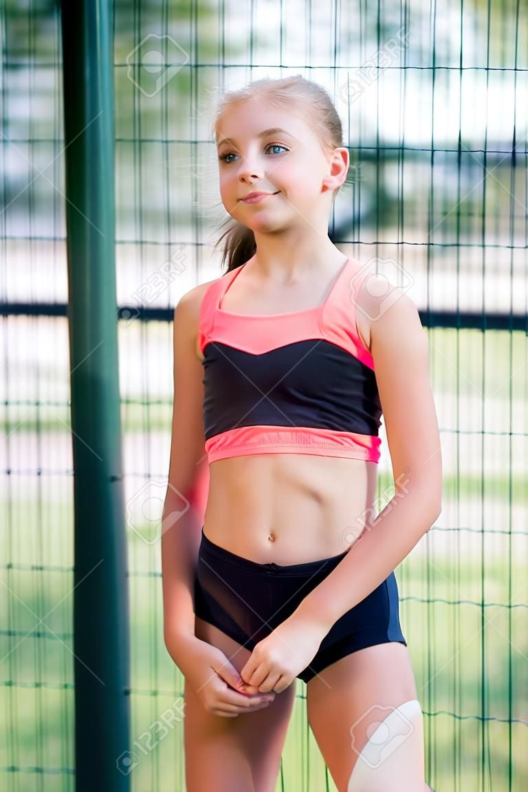 Une jeune fille sympathique au corps élancé, vêtue d'une forme de sport, effectue des exercices en plein air